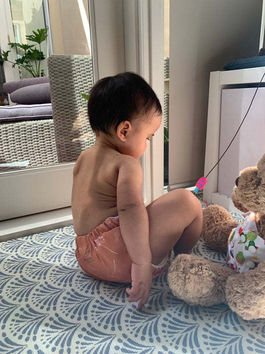 Baby wearing cloth nappy next to teddy bear