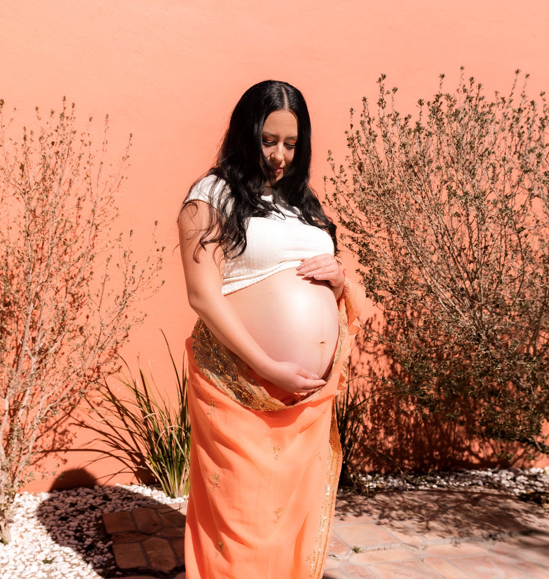 pregnant woman in green dress holding her baby bump